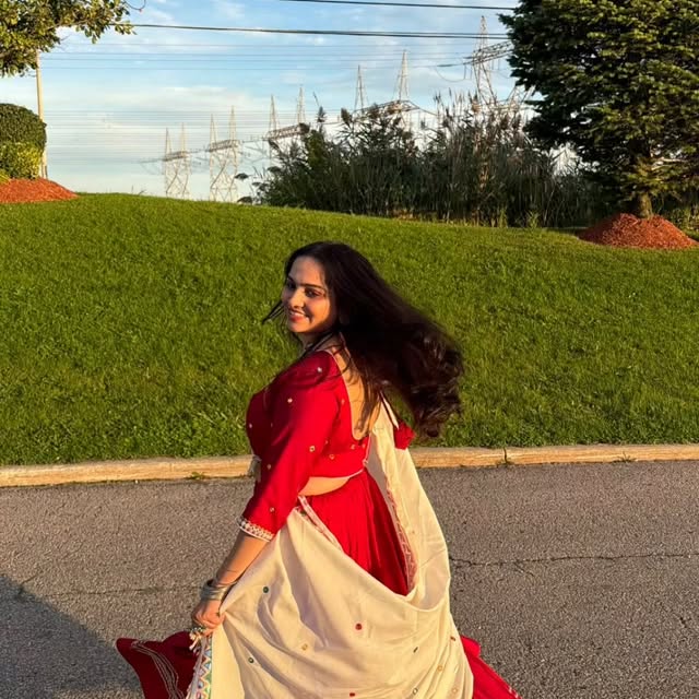 Woman twirling in a red chaniya choli with ivory mirror-work dupatta